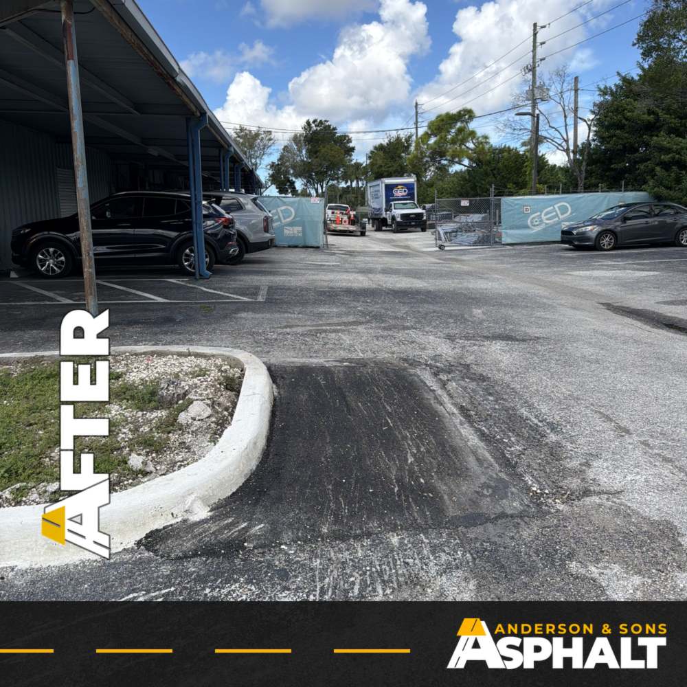 New asphalt patch at the end of a curbed island in a commercial parking lot drive lane