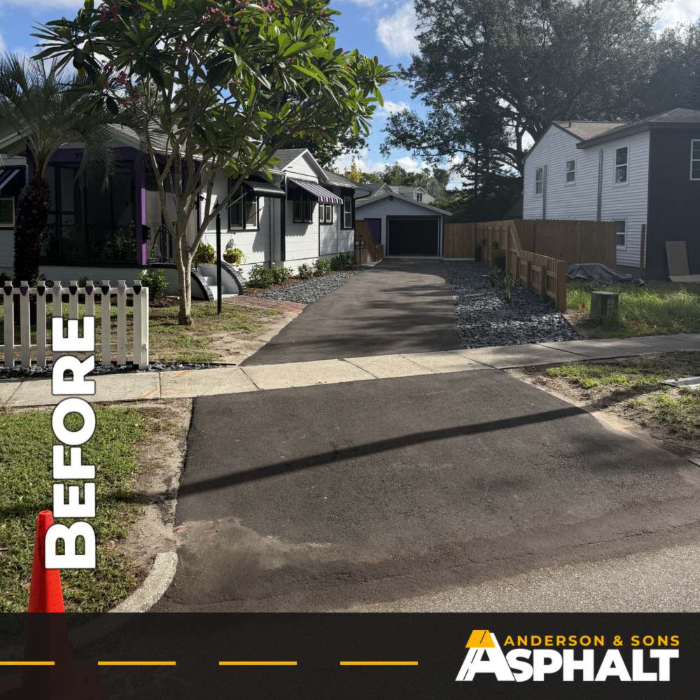 Faded gray asphalt driveway leading to a detached garage, before sealcoating