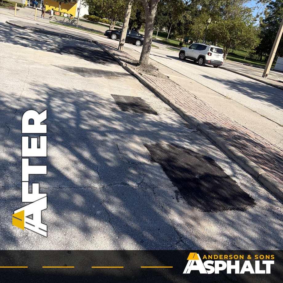 Fresh asphalt patches in parking stalls along a brick-paved island under shade trees