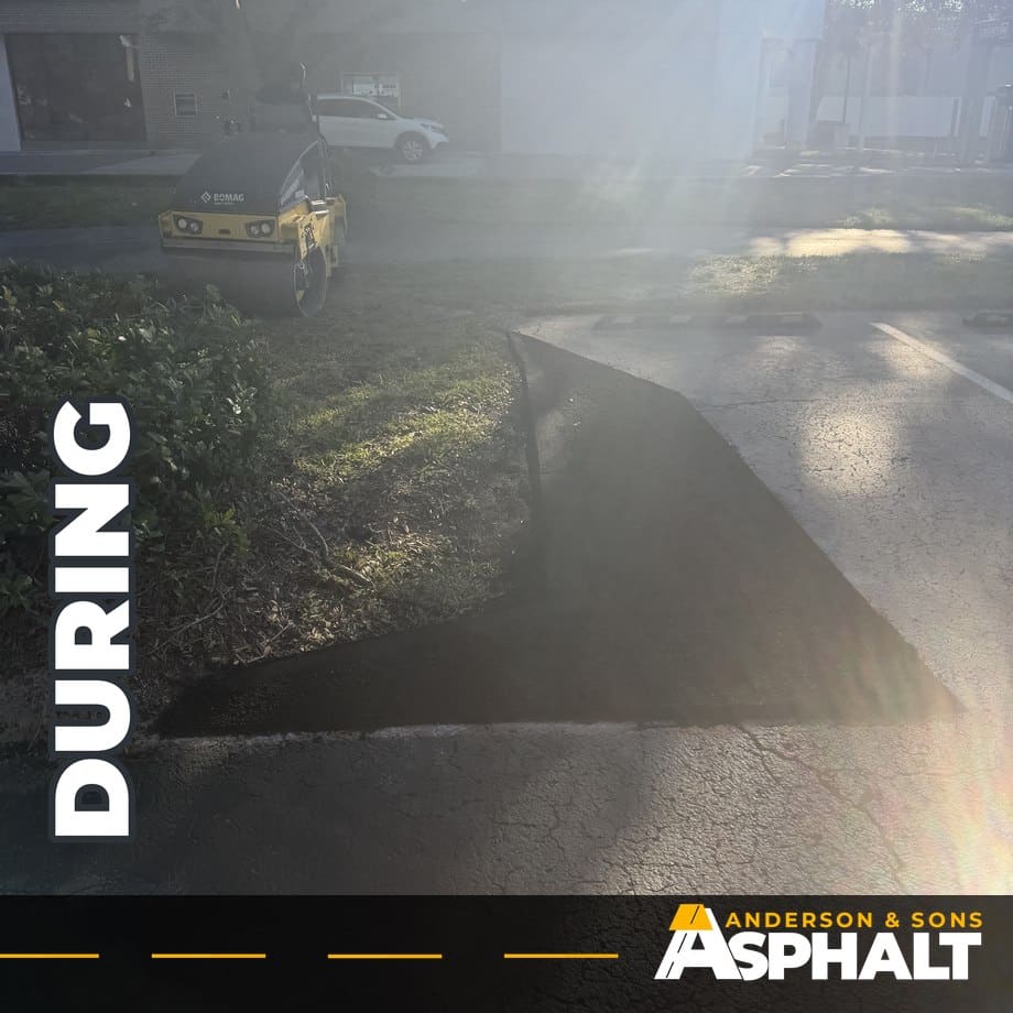 Freshly placed asphalt along a parking lot island with a roller parked nearby